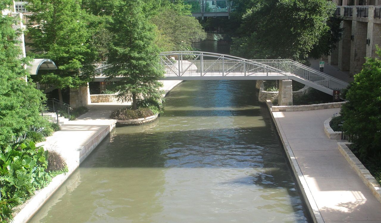 San Antonio River Walk with pedestrian bridge and lush greenery