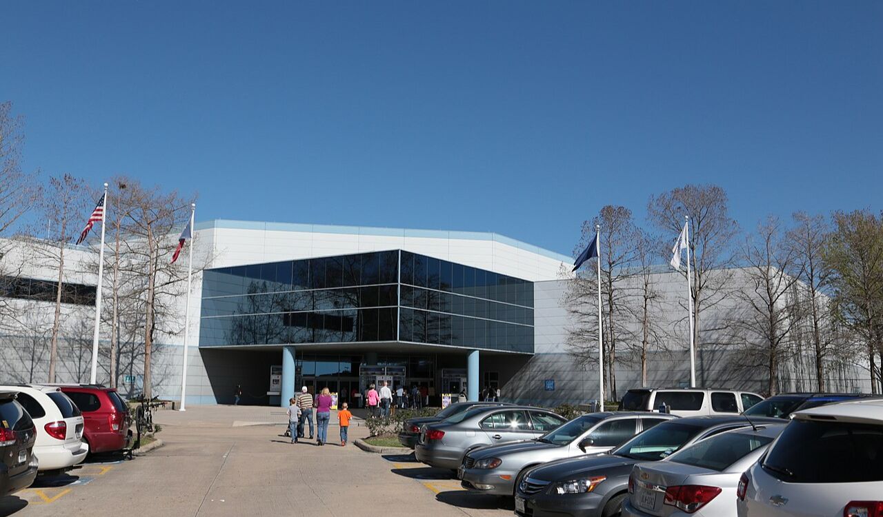 Space Center Houston entrance with visitors and parked cars
