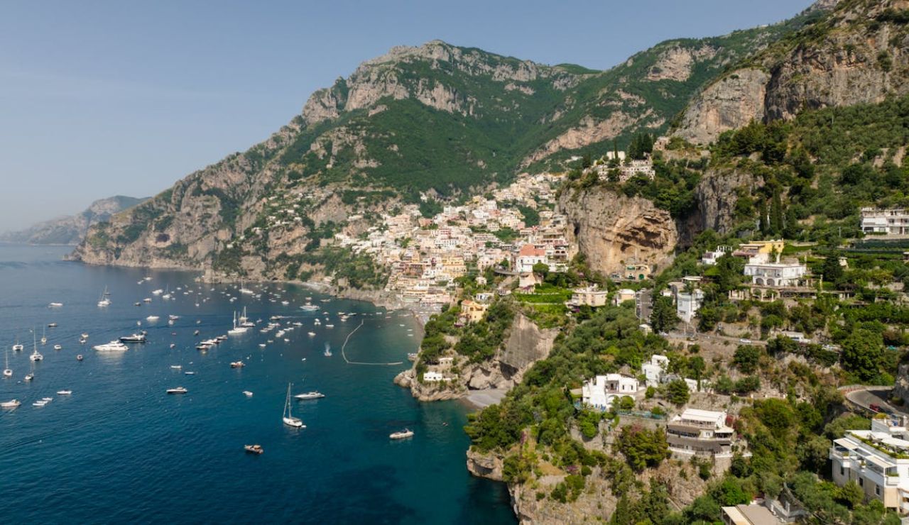Aerial view of Positano, a picturesque village on Italy’s Amalfi Coast, with colorful cliffside buildings and boats anchored in the deep blue Mediterranean Sea.