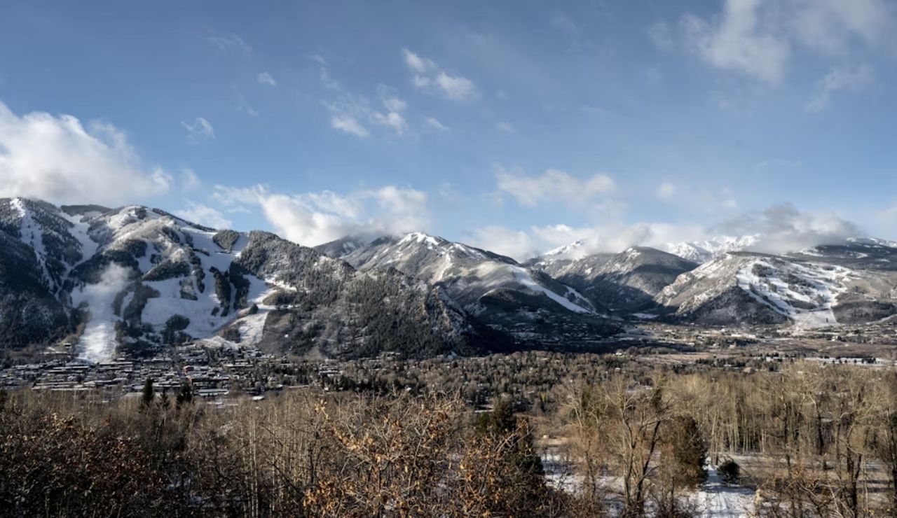 Panoramic view of Aspen, Colorado with snow-covered ski slopes, mountain peaks, and the town nestled in the valley.