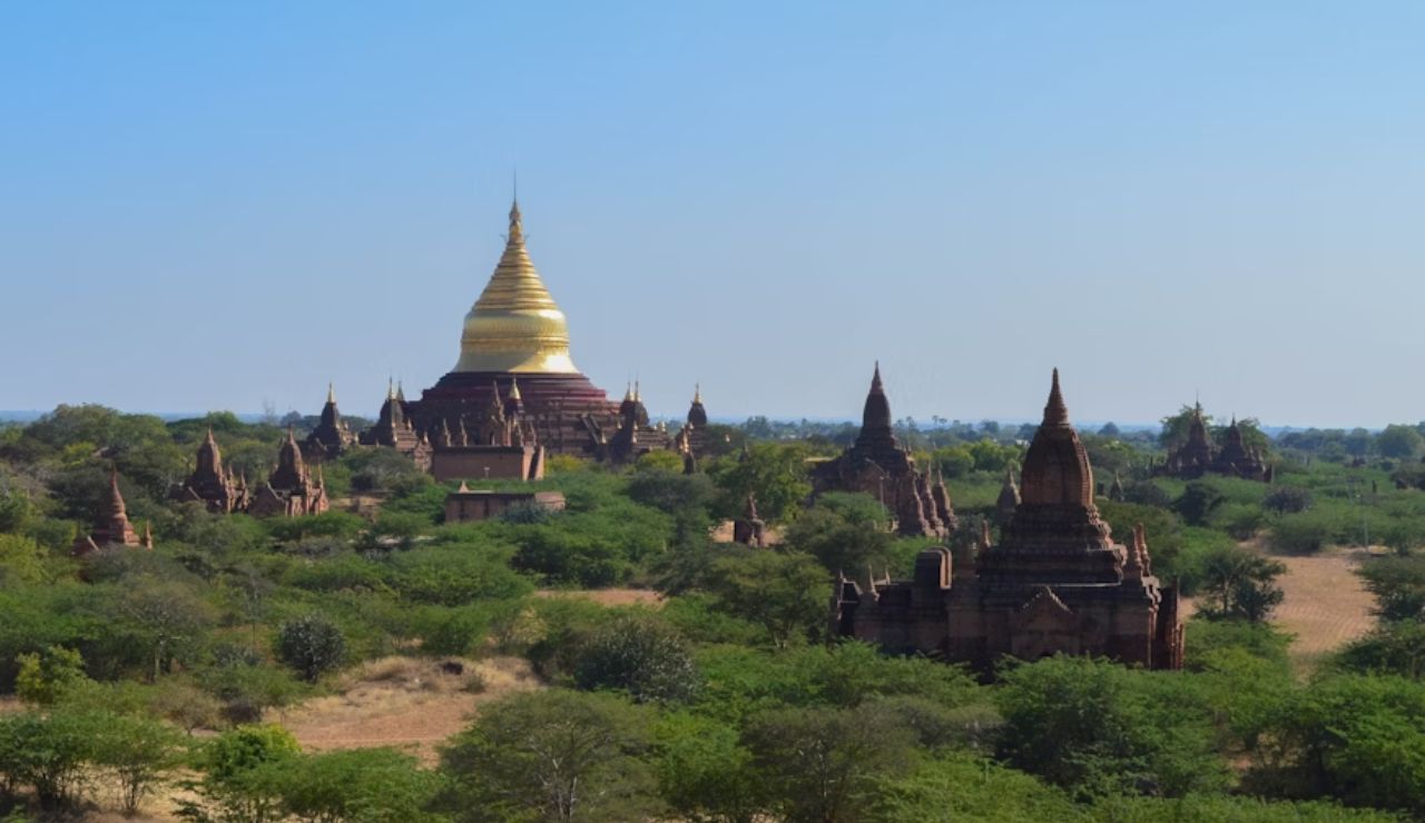 Ancient temples and golden pagoda of Bagan, Myanmar under a clear sky.