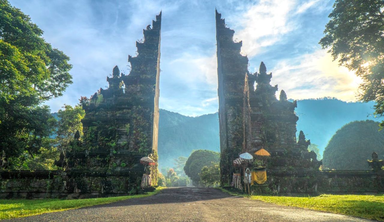 Traditional Balinese split gate surrounded by lush greenery and morning light.