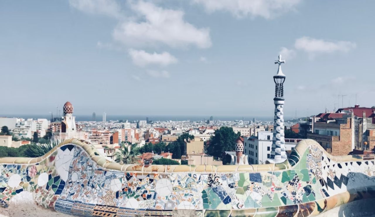 Colorful mosaic bench overlooking cityscape and sea in Park Güell, Barcelona.