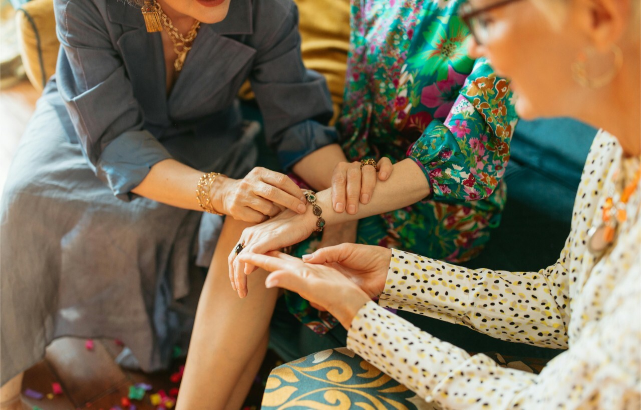 Women admiring a bracelet in a colorful setting.