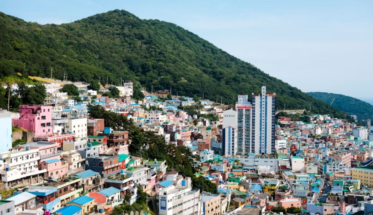 Colorful hillside buildings in Gamcheon Culture Village, Busan, South Korea, with forested mountains in the background.