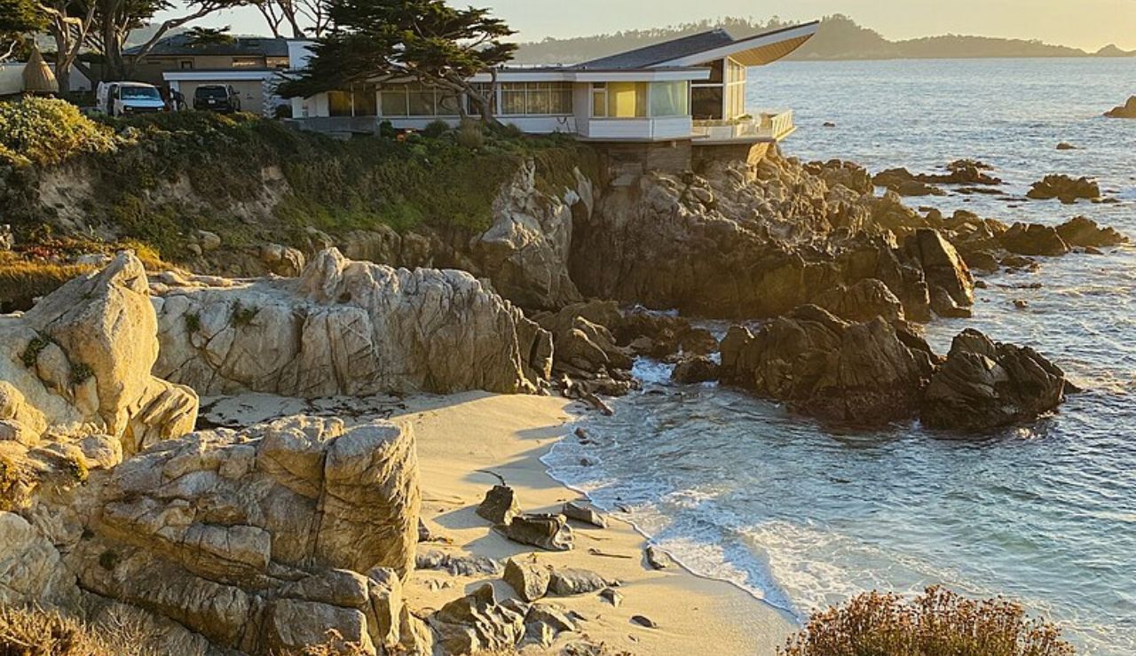 Modern coastal home perched on rocky cliffs overlooking the Pacific Ocean at sunset in Carmel-by-the-Sea, California