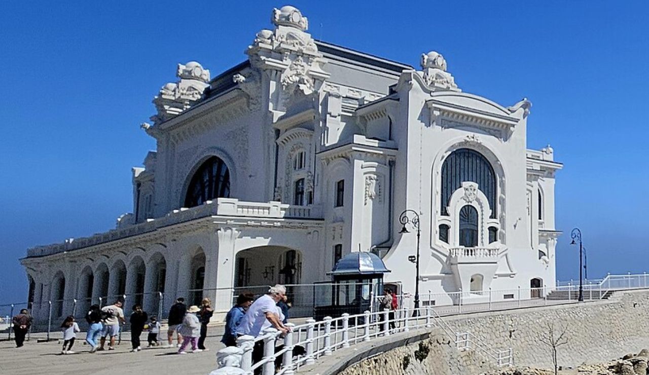 Restored Constanța Casino in Romania with visitors along the seafront promenade.
