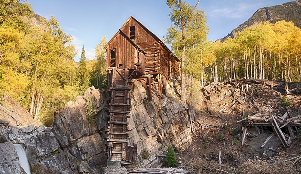 Crystal Mill, a historic wooden powerhouse perched on a rocky ledge in Colorado's backcountry forest.
