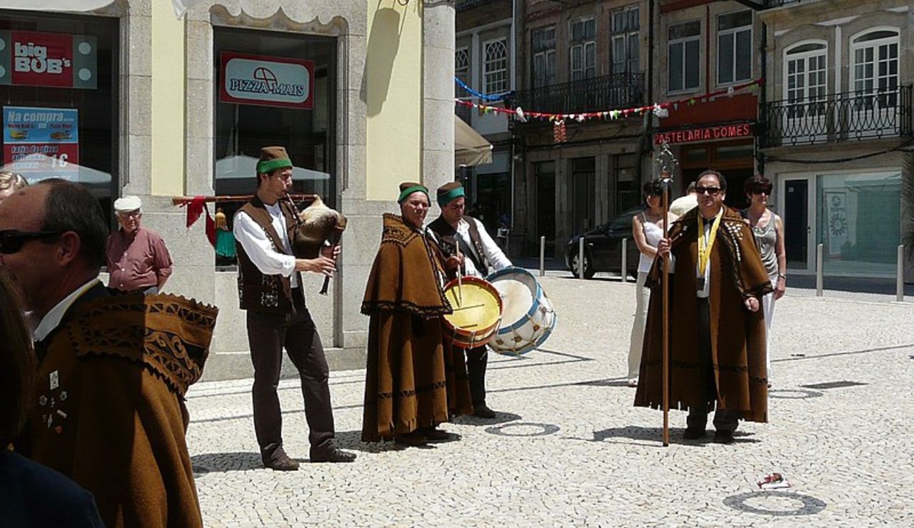 Traditional Portuguese musicians in folk costumes performing in a city square.