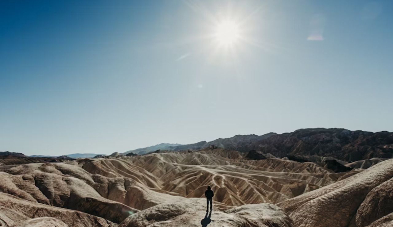 A person standing in the vast, sunlit landscape of Death Valley.