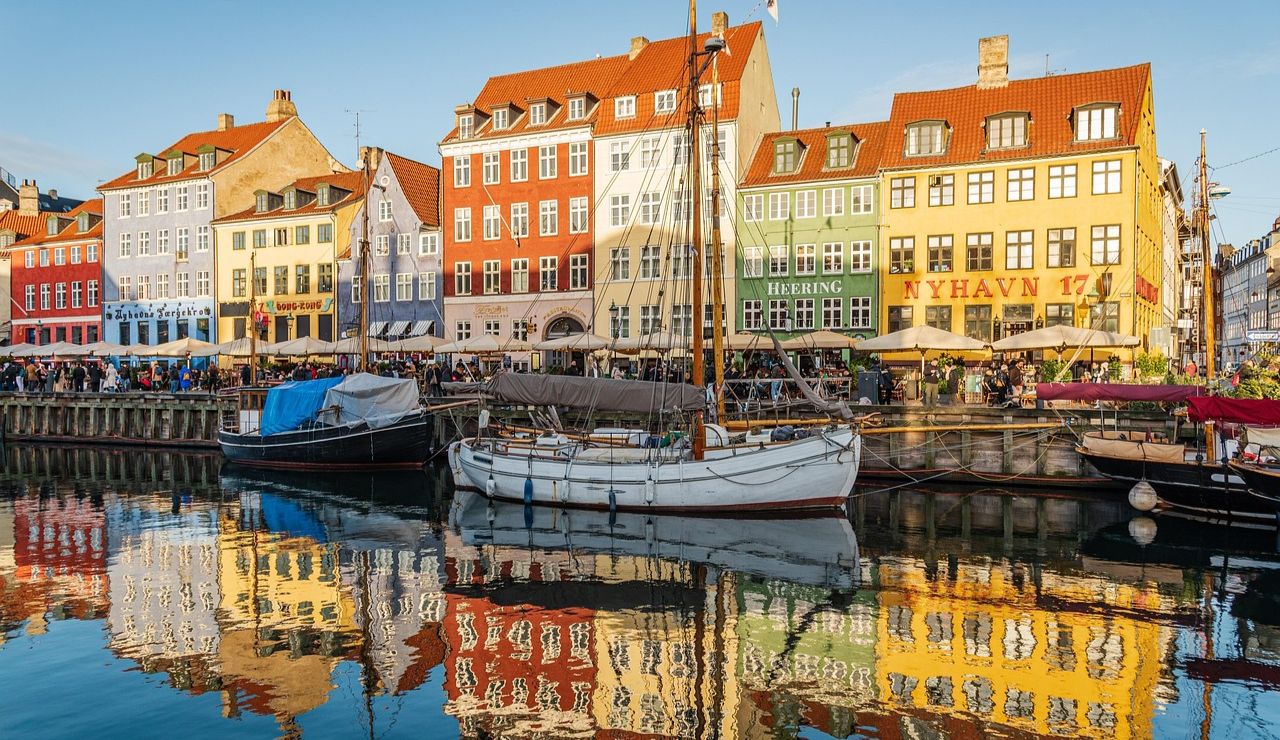 Colorful buildings and boats reflected in the Nyhavn Canal in Copenhagen, Denmark.