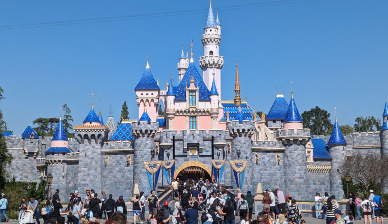 Front view of Sleeping Beauty Castle at Disneyland in Anaheim, California, with crowds of visitors under a clear blue sky