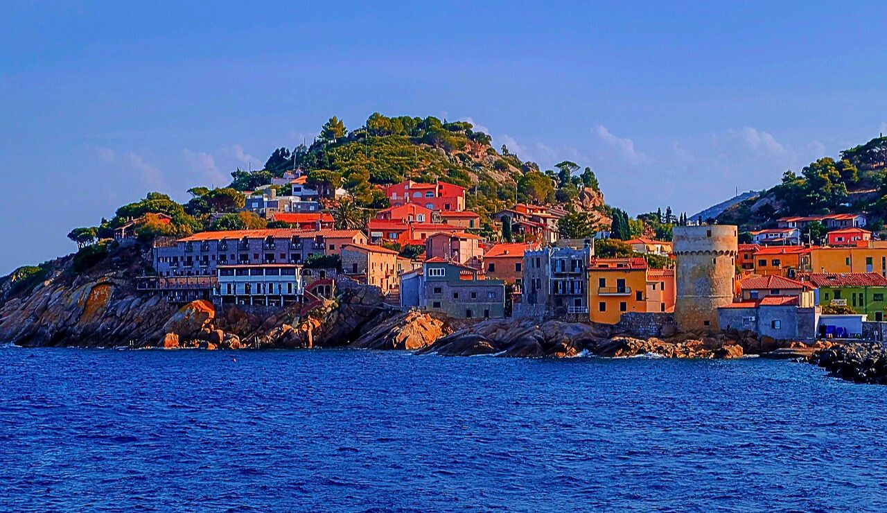 Small boats bob in a pastel-painted harbor on Elba Island, Italy.