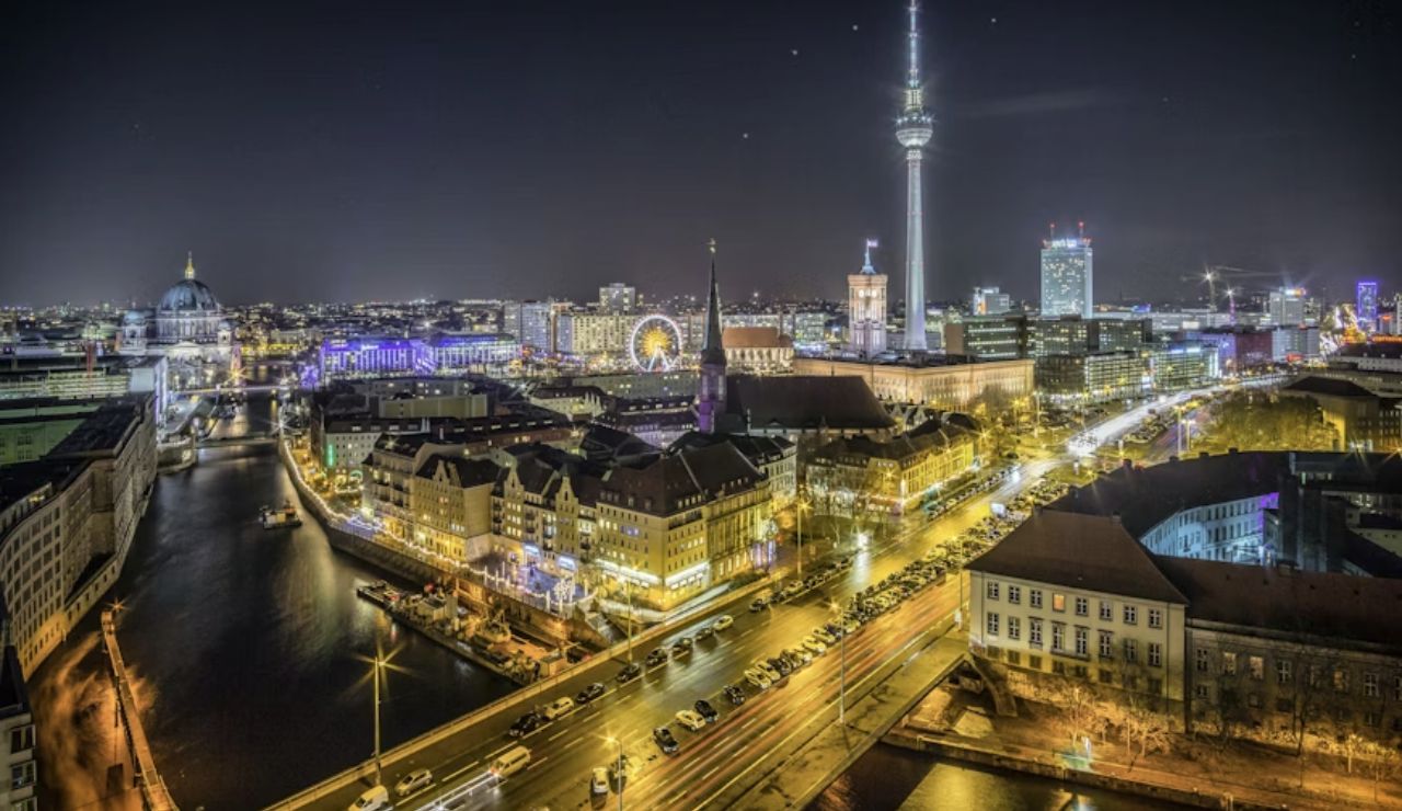 Night view of Berlin cityscape featuring the Berlin TV Tower, cathedral, and illuminated streets.