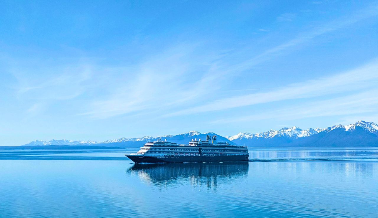 A cruise ship sails through Glacier Bay surrounded by floating icebergs and dramatic snow-covered mountain ranges.