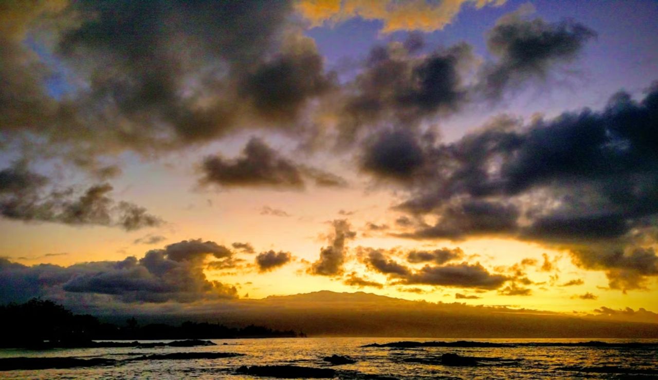 Sunset over the ocean with dramatic clouds and Mauna Kea in the background, viewed from Hilo, Hawaii.