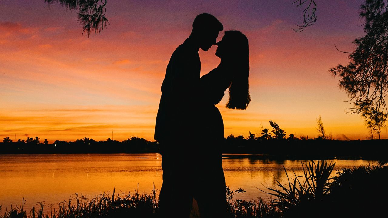 A couple hand-in-hand at sunset, bathed in golden light.