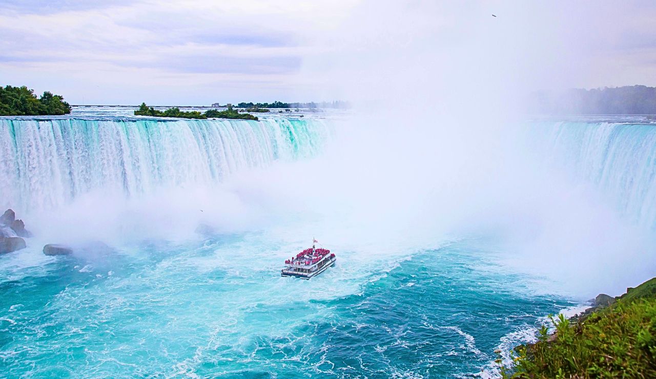 View of Horseshoe Falls from a tour boat surrounded by mist and rushing water.