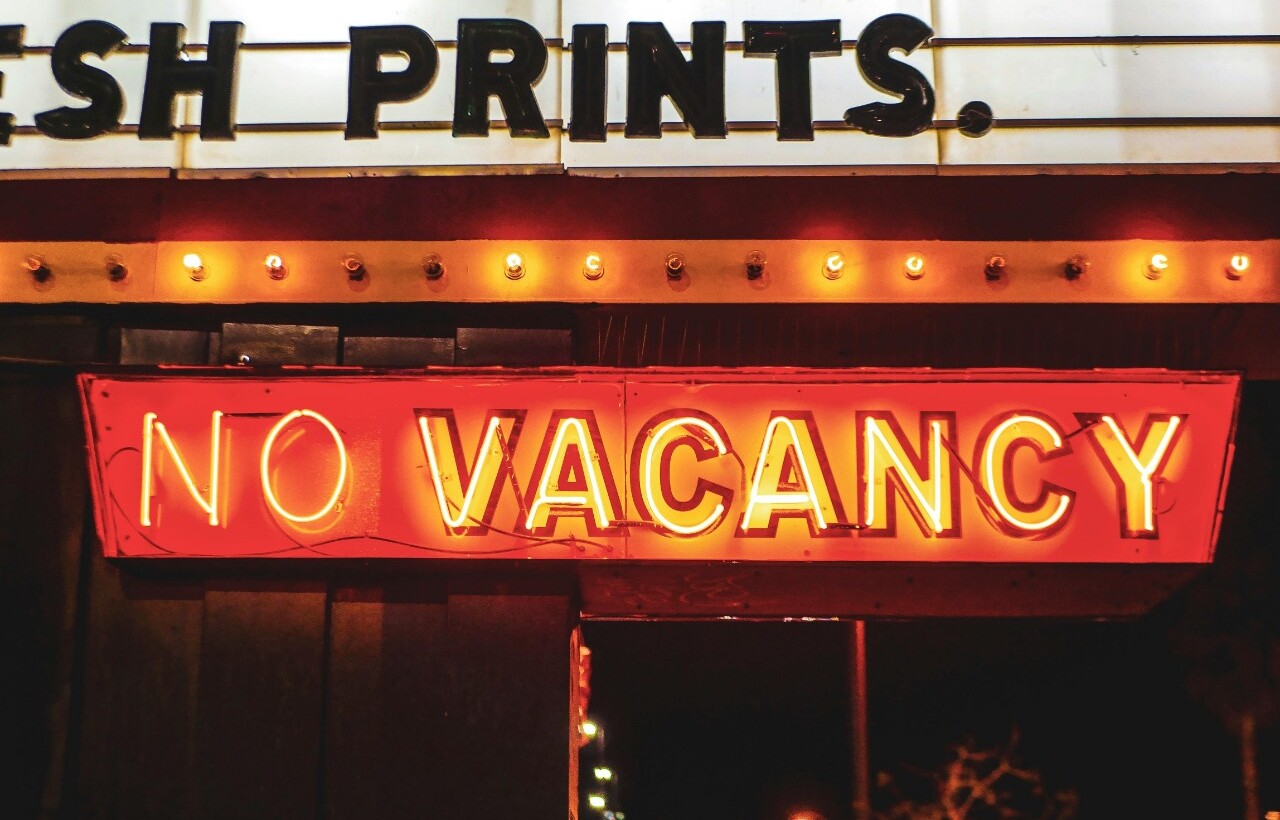 Neon “No Vacancy” sign outside a hotel at night.
