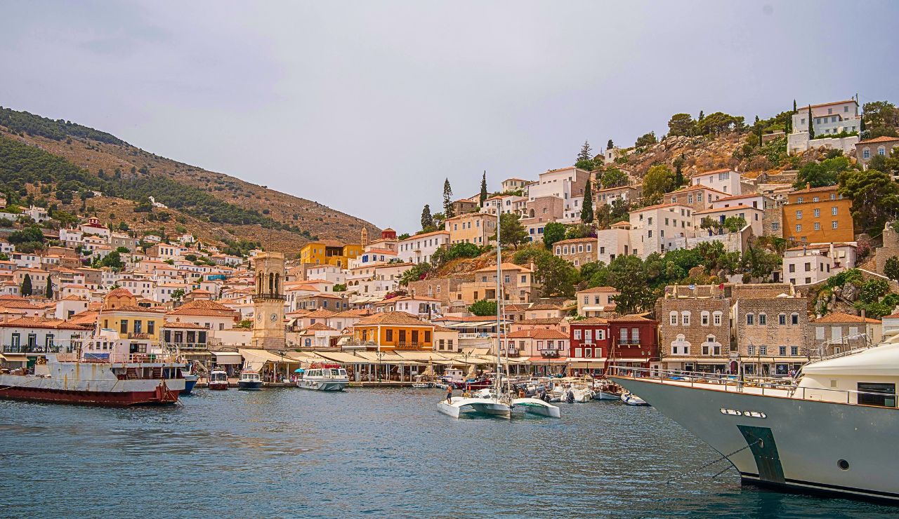 Donkey waits on Hydra’s cobbled harbor with whitewashed homes behind.
