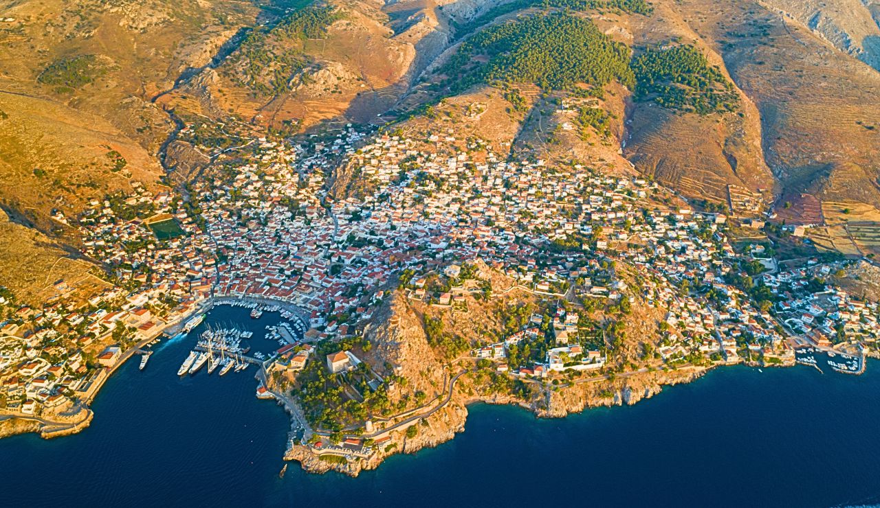 Donkey waits on Hydra’s cobbled harbor with whitewashed homes behind.
