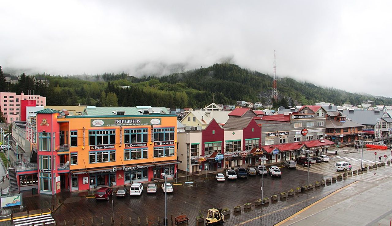 Colorful waterfront buildings in downtown Ketchikan, Alaska on a rainy day, with mist-covered forested hills in the background.