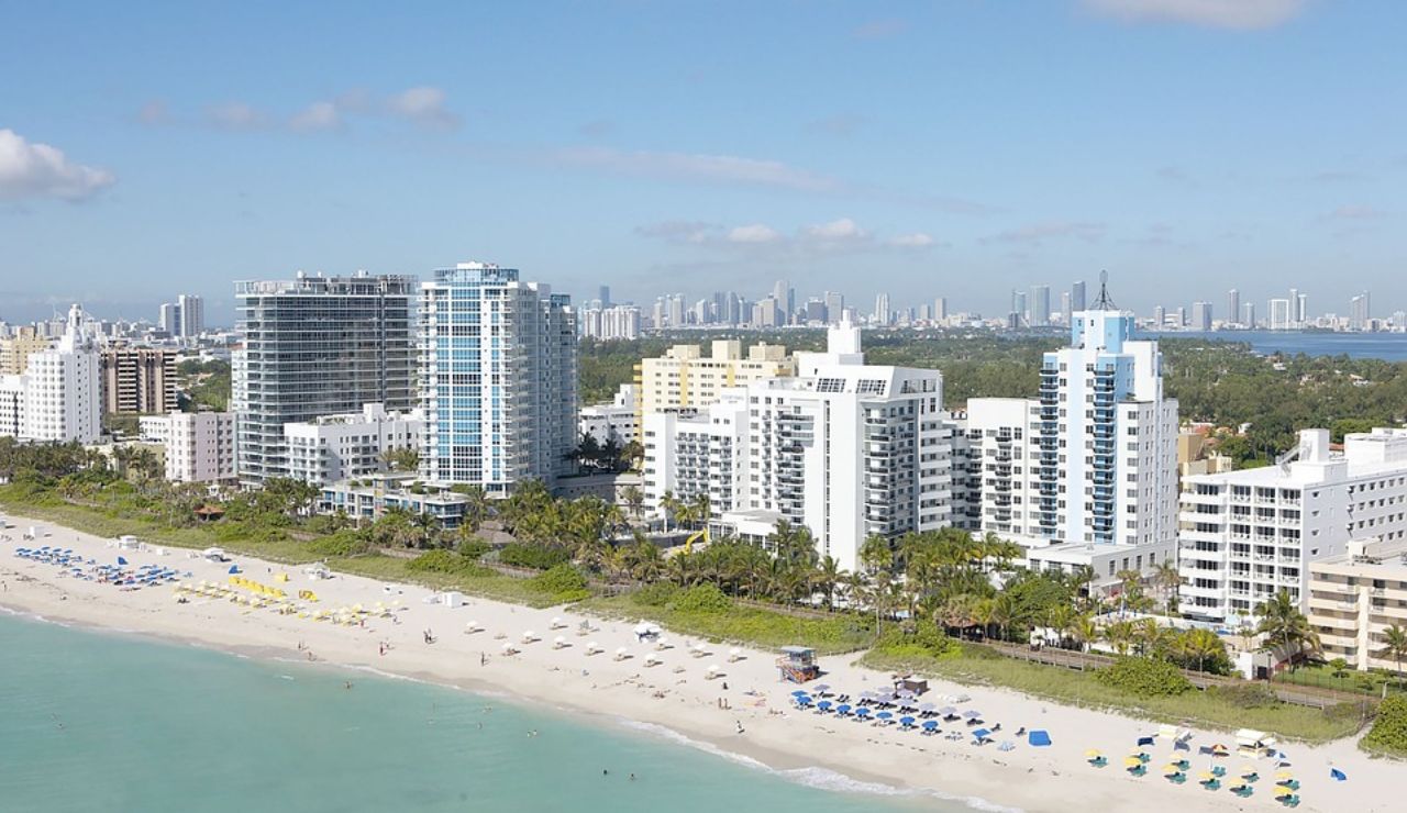 Aerial view of beachfront hotels and umbrellas along a sunny coastline.