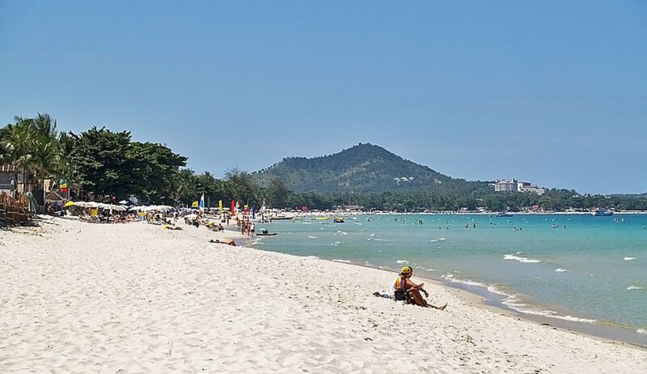 Tourists relax and enjoy the sun along the white sands of Chaweng Beach in Koh Samui, Thailand.