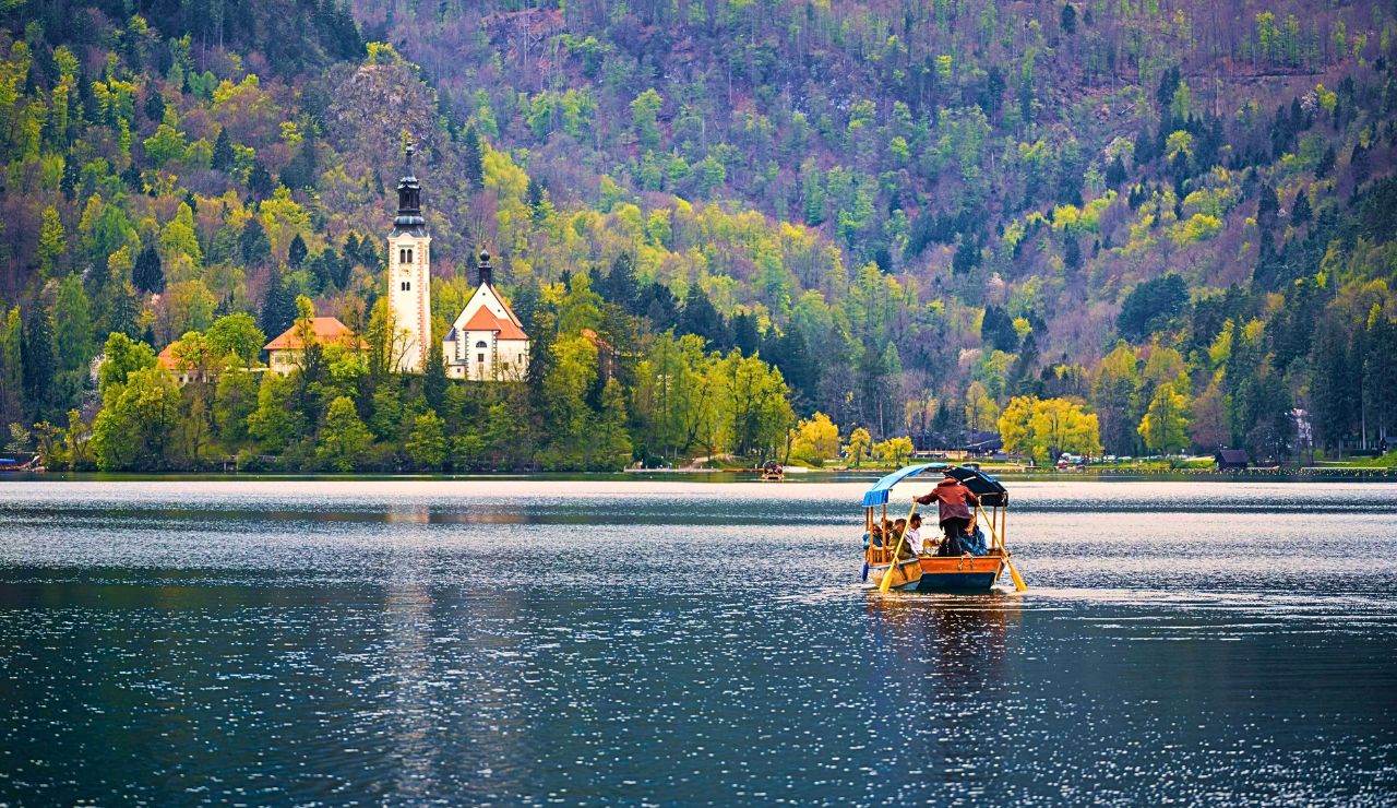 Row Boats floating on Lake Bled with the island church in the background, surrounded by autumn trees.
