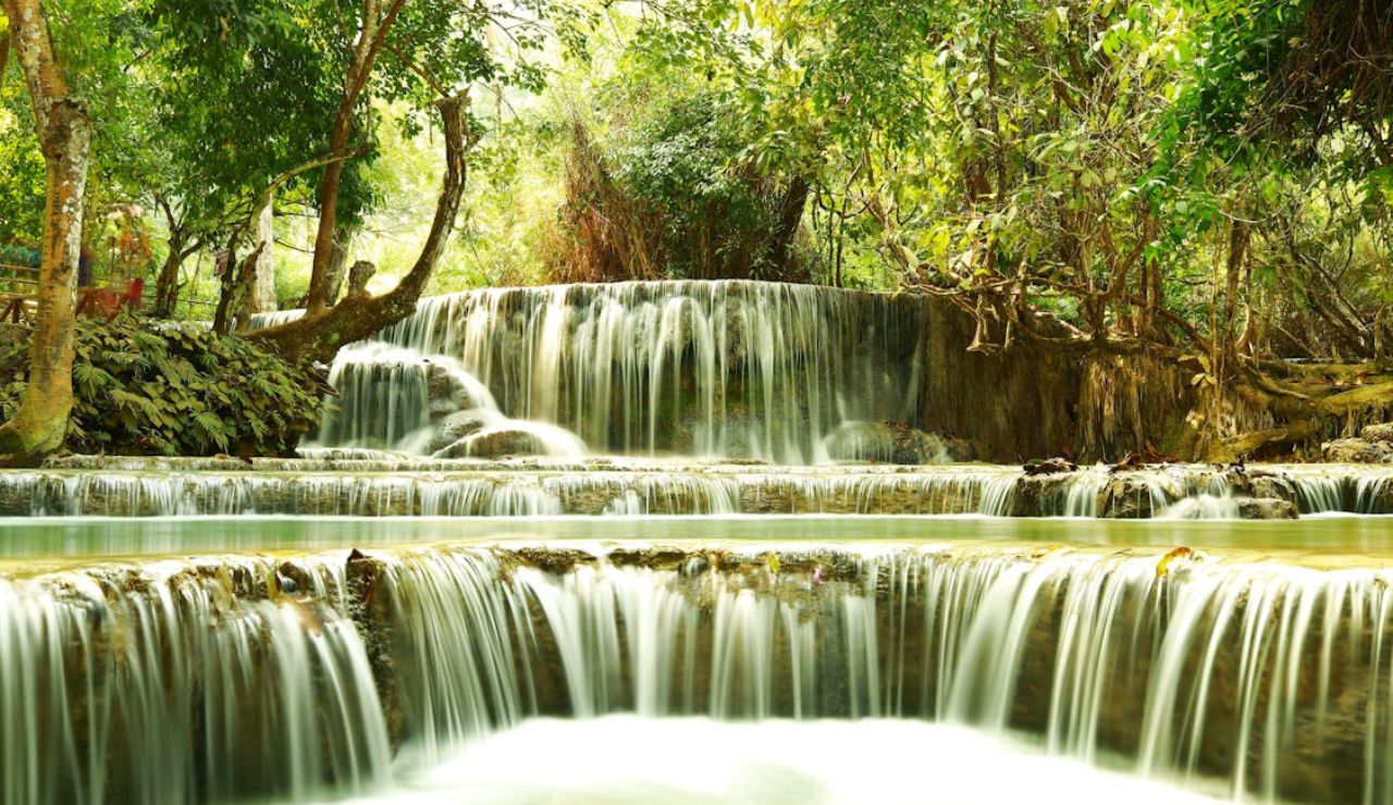 Scenic multi-tiered Kuang Si Falls surrounded by lush jungle in Luang Prabang, Laos.