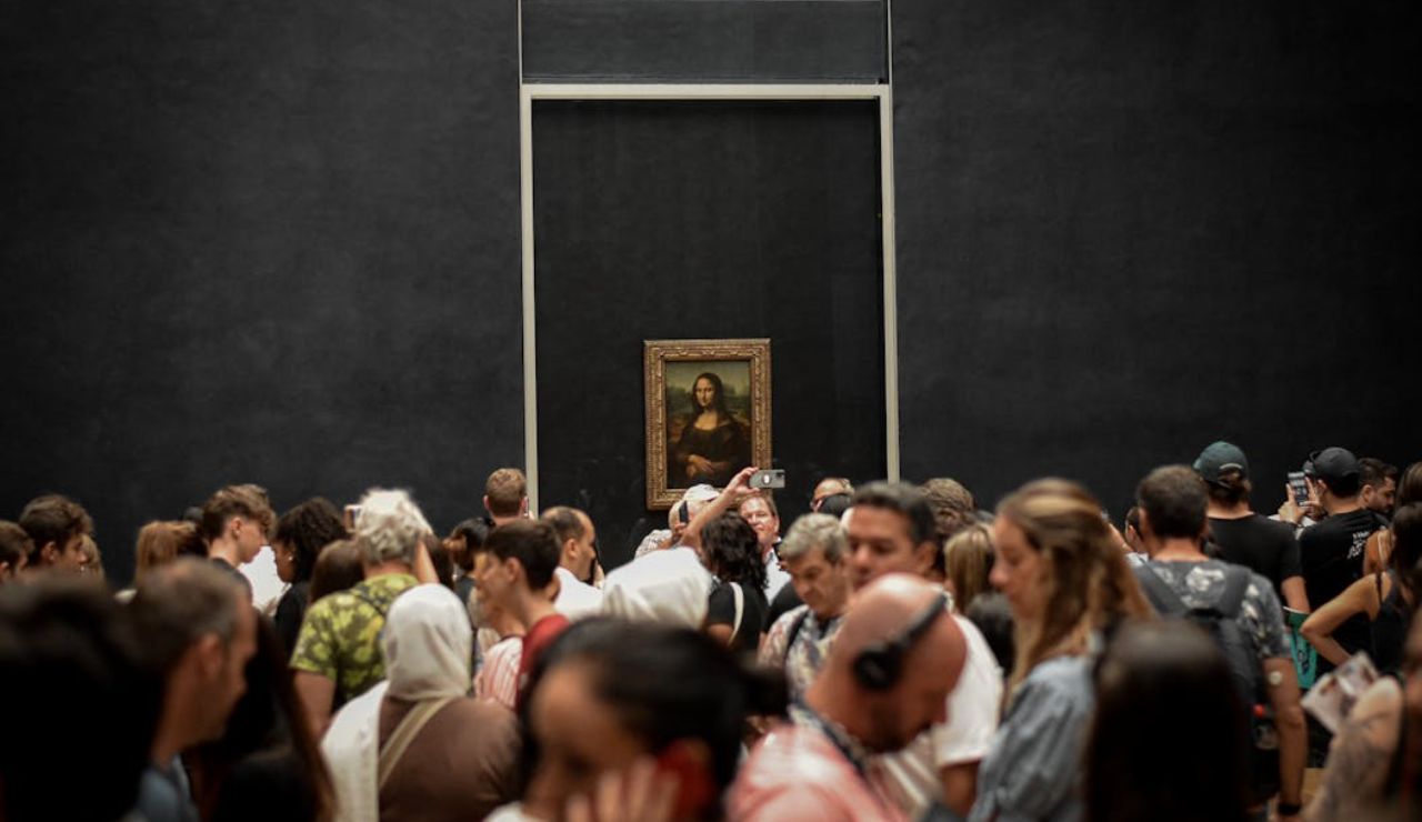 Crowds gather to view and photograph the Mona Lisa at the Louvre Museum.