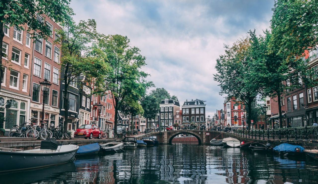 Boats docked along a scenic canal lined with historic buildings in Amsterdam, Netherlands.