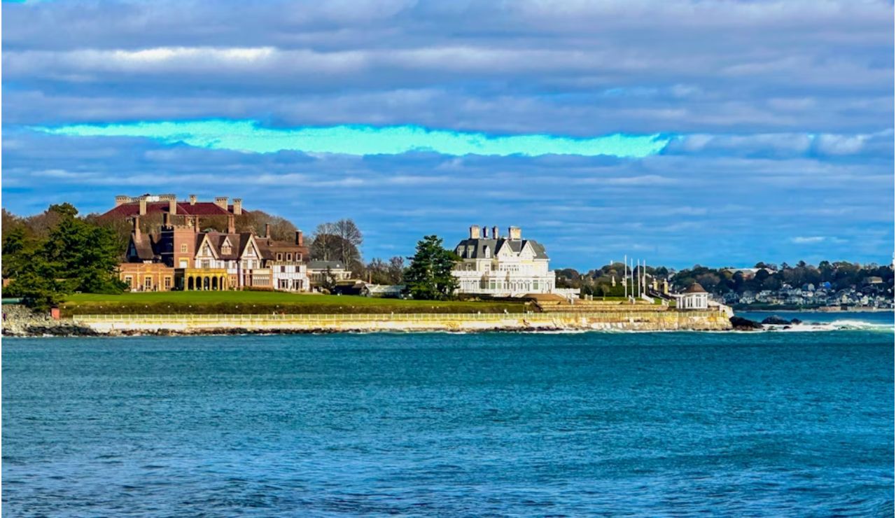 Elegant historic mansions overlooking the ocean along the scenic Newport, Rhode Island coastline under a partly cloudy sky