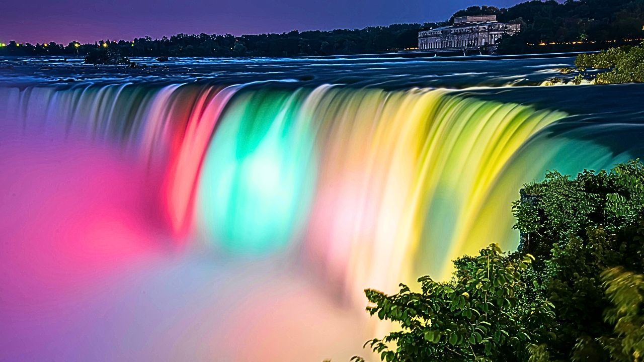 Sunset view of Niagara Falls with mist rising and warm light reflecting on the water.