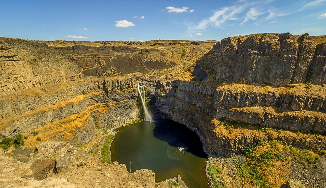 Palouse Falls plunging into a canyon surrounded by golden hills
