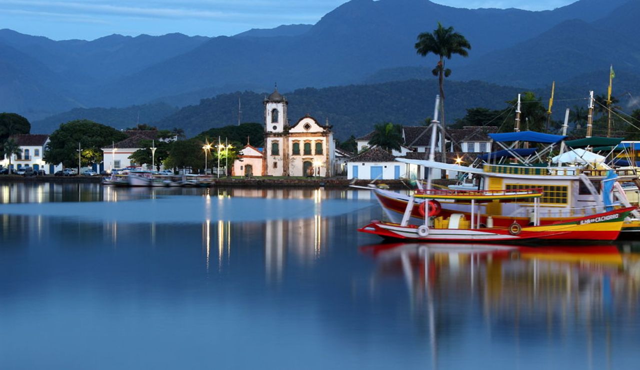 Colorful boats and colonial buildings reflected in the calm waters of Paraty, Brazil.