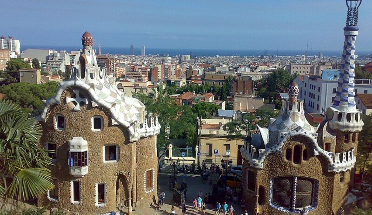 Visitors explore the whimsical architecture of Park Güell in Barcelona with a panoramic city and sea view.