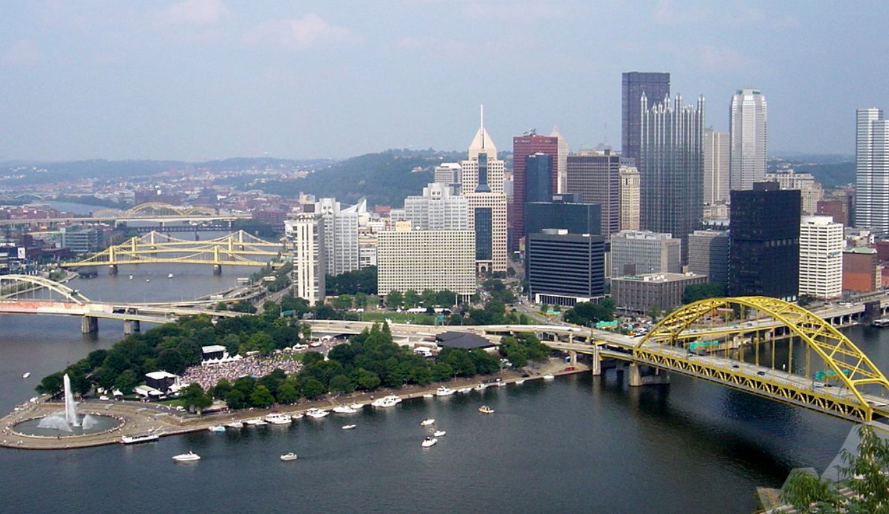 Aerial view of downtown Pittsburgh, Pennsylvania, featuring the city skyline, yellow bridges, and Point State Park at the confluence of three rivers.