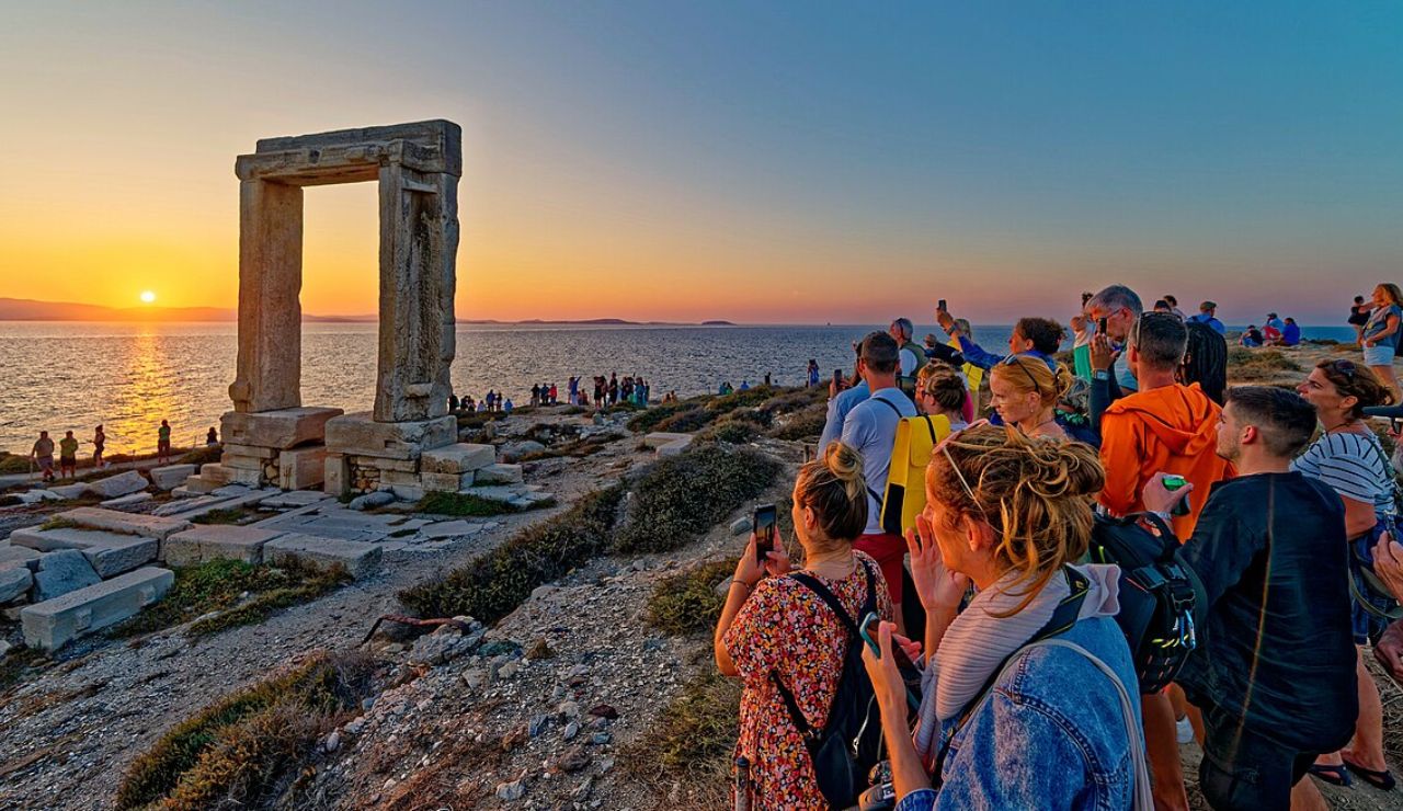 Tourists watch the sunset at the Portara ruins on Naxos Island, Greece.