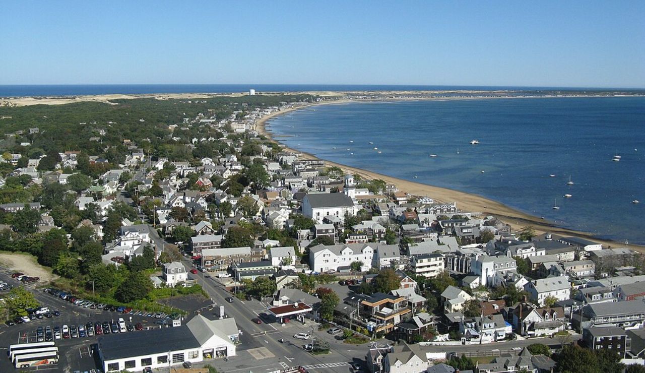 Aerial view of a coastal town with sandy beach and docked boats.