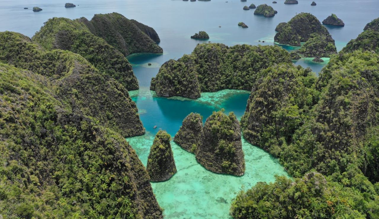 Aerial view of the stunning limestone karst islands and turquoise lagoons of Raja Ampat, Indonesia, surrounded by the Pacific Ocean.