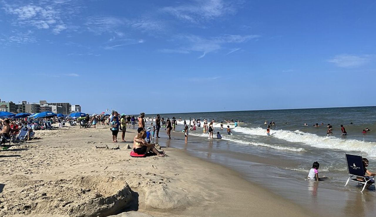 Crowded summer beach day at Rehoboth Beach, Delaware, with people enjoying the waves.