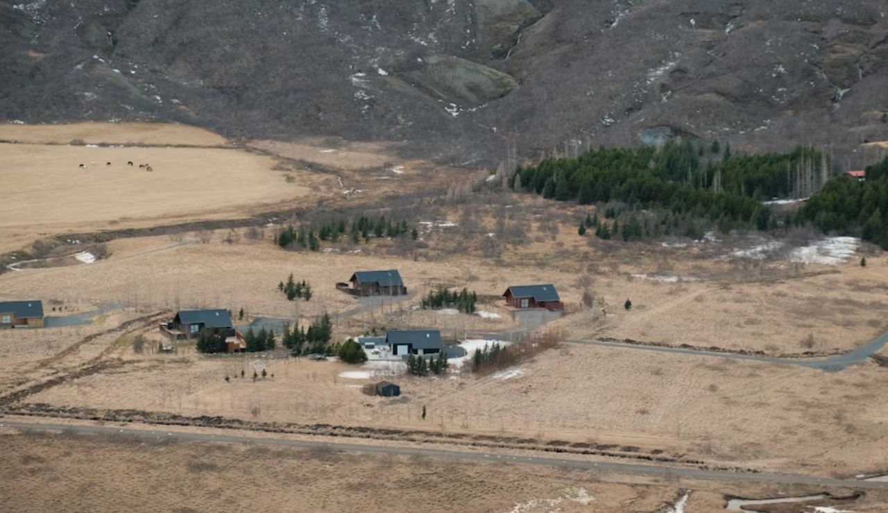 Scattered rural cabins in a dry valley with patches of snow and trees.