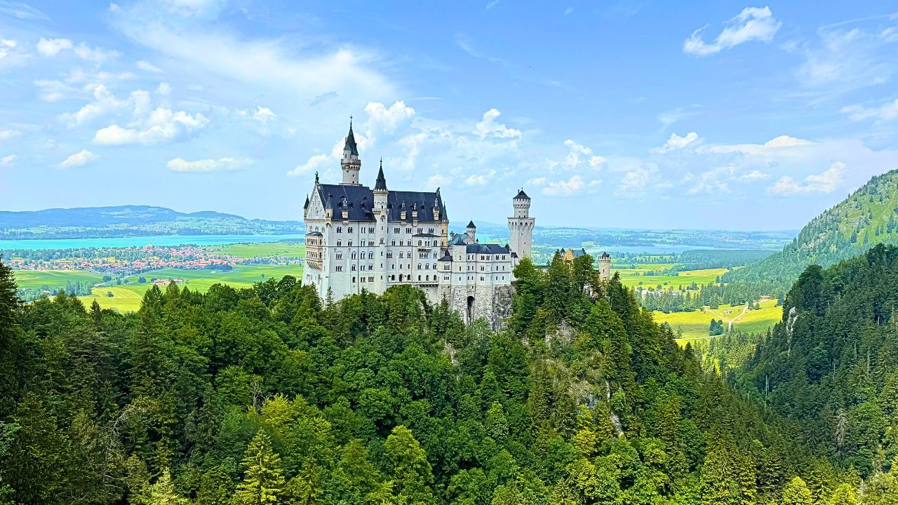 A remote medieval castle perched on a mountain ridge, surrounded by fog and hills