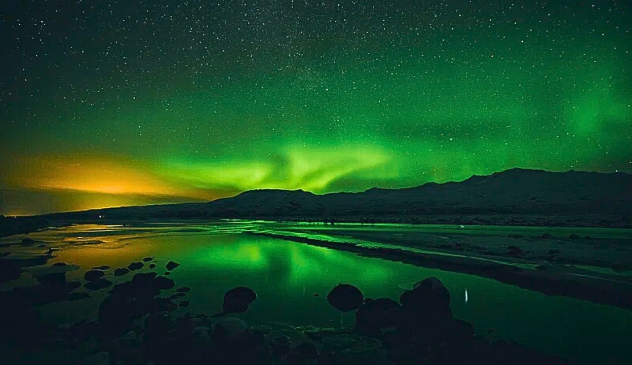 Northern lights dancing above Reykjavik's snowy landscape and colorful rooftops. Slide Text
