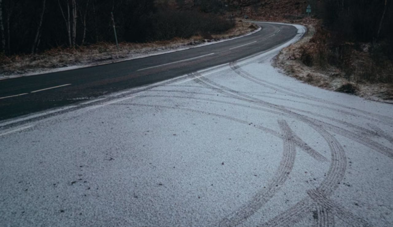 Curved icy road in Canada with visible tire tracks and snowy surface