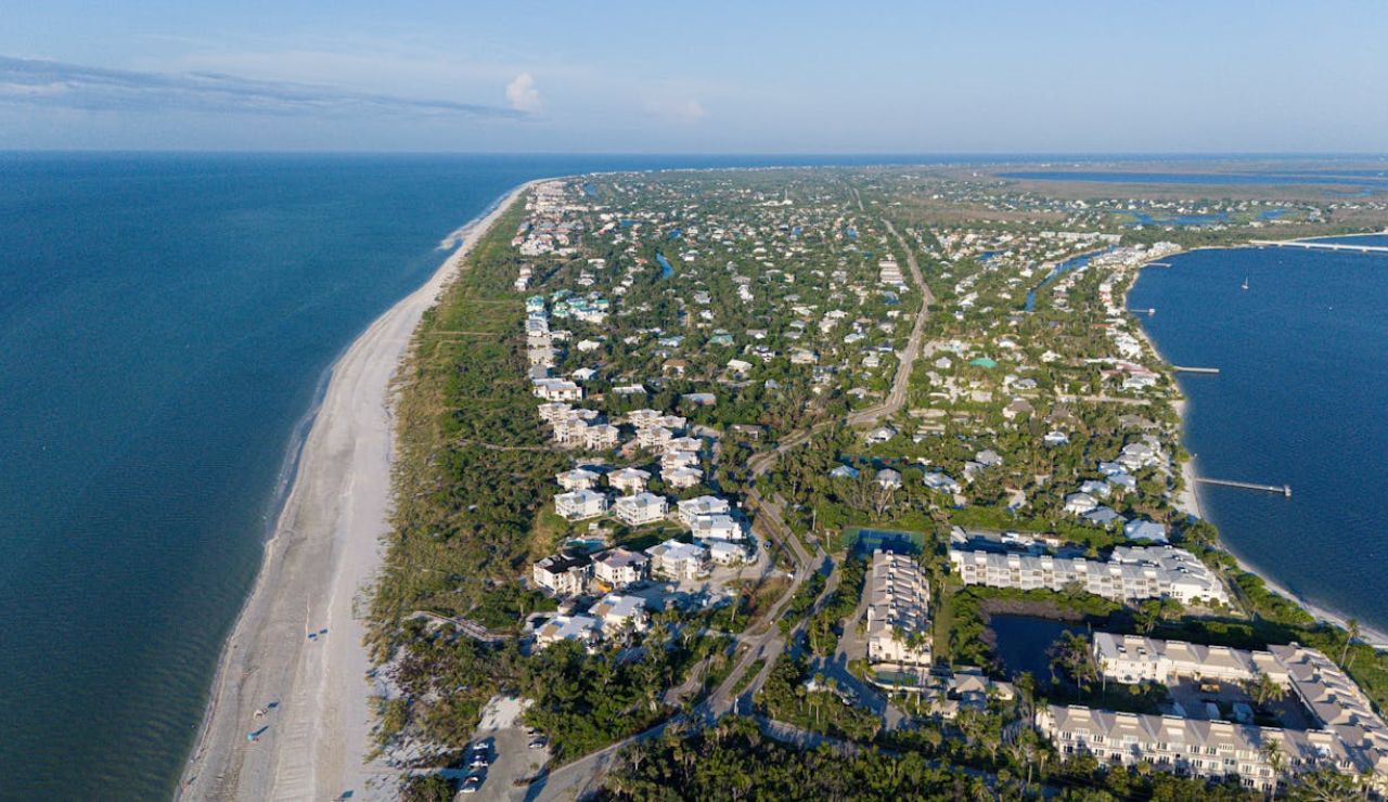 Aerial view of Sanibel Island, Florida, with beachfront homes and lush greenery.