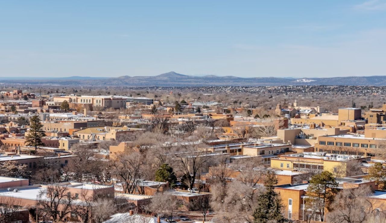 Aerial view of Santa Fe, New Mexico with adobe-style buildings and distant mountains on a clear winter day