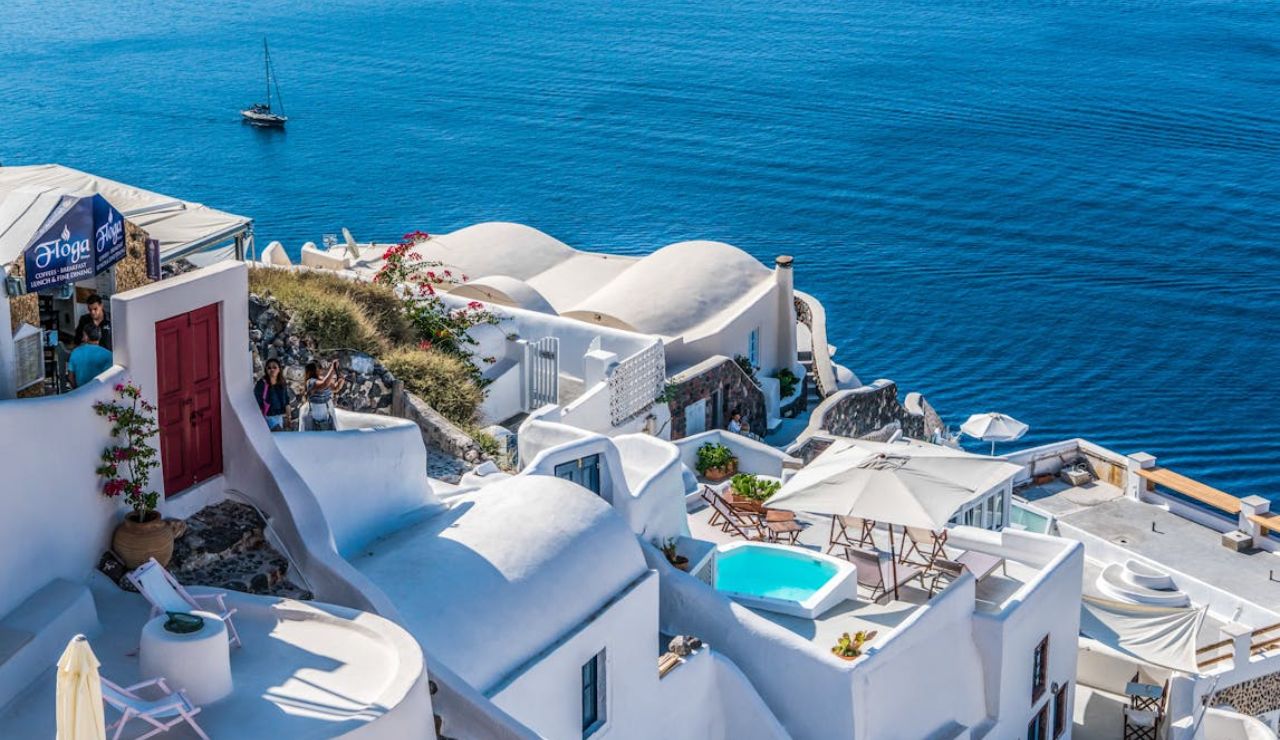 Whitewashed buildings with pools and sea view in Santorini, Greece.