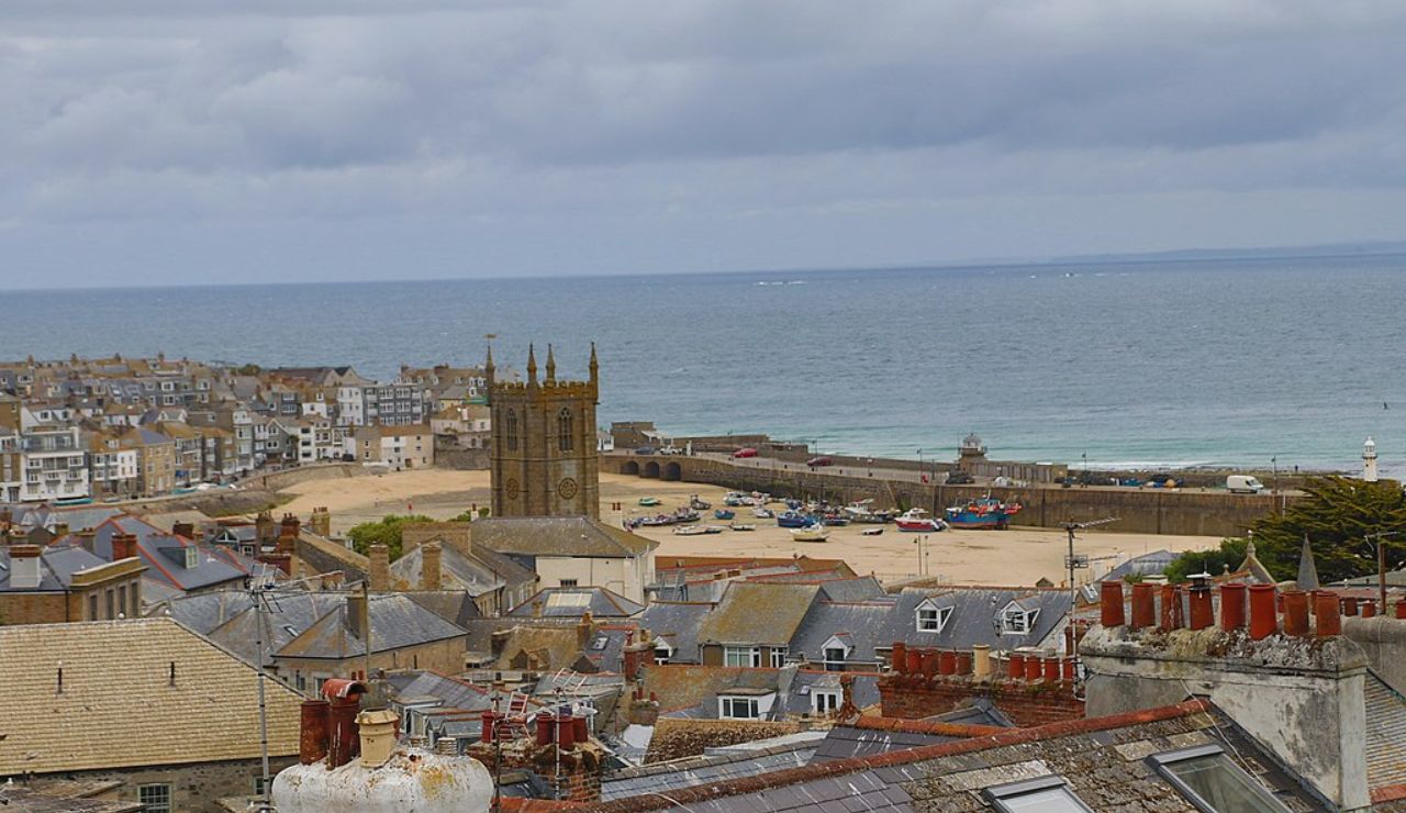 Seaside town of St Ives, England, with historic rooftops and a sandy harbor.